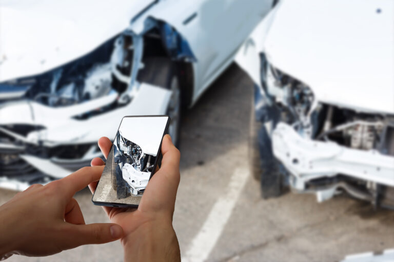 Driver documenting vehicle damage after a crash